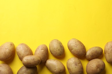 Photo of Many fresh potatoes on yellow background, flat lay. Space for text