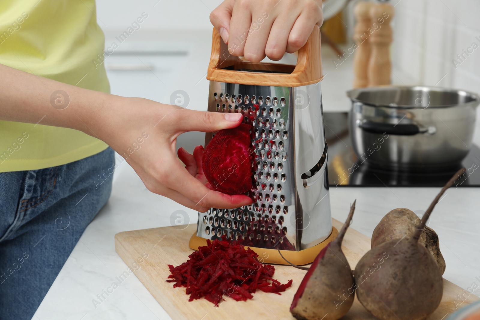 Photo of Woman grating fresh beetroot at kitchen counter, closeup