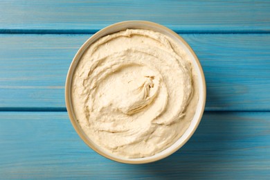 Tasty hummus in bowl on light blue wooden table, top view