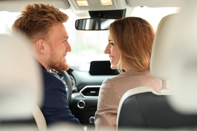 Happy young man and woman in modern car, back view