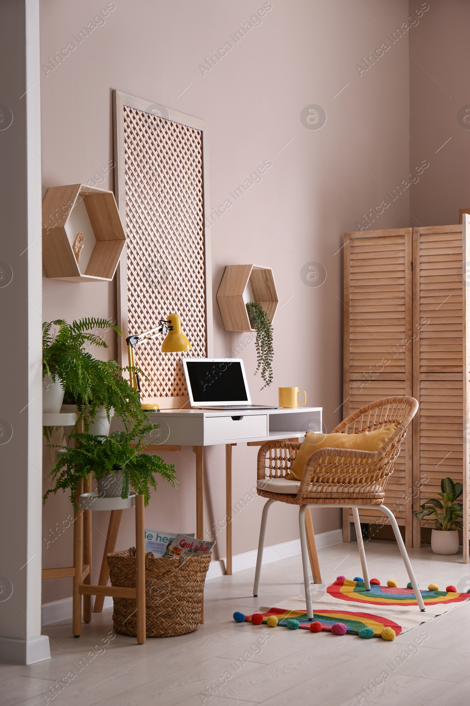 Photo of Comfortable workplace with modern laptop and houseplants in room. Interior design