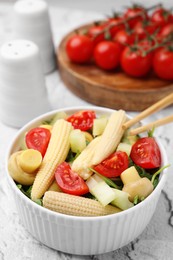 Tasty baby corn with vegetables and champignons on grey textured table, closeup