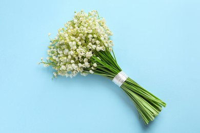 Photo of Beautiful lily of the valley bouquet on light blue background, top view