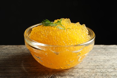 Photo of Fresh pike caviar in bowl on wooden table, closeup