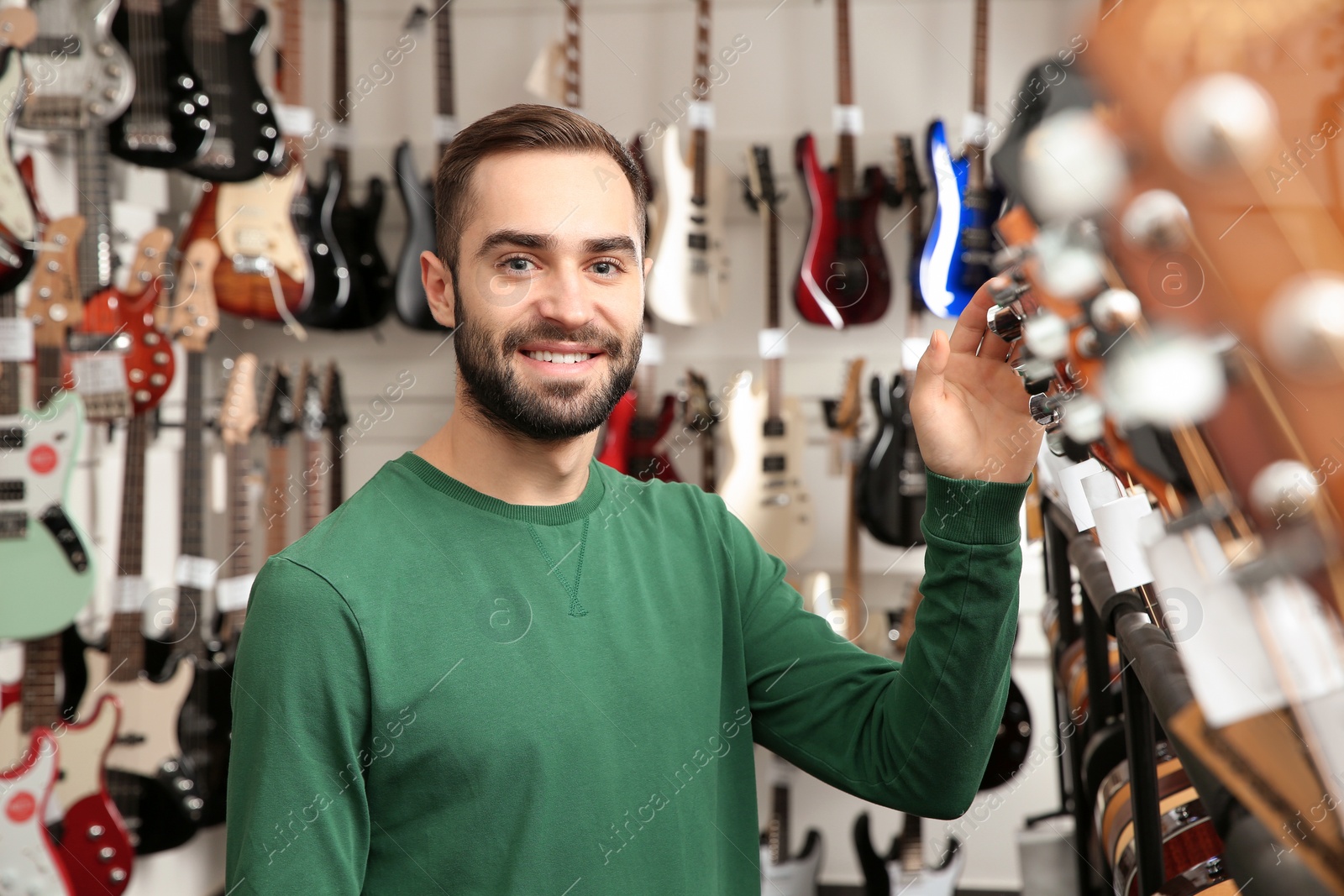 Photo of Buyer choosing guitar in modern music store