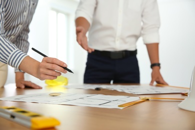 People working with construction drawings at table, closeup