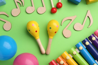 Photo of Tools for creating baby songs. Flat lay composition with maracas on green background