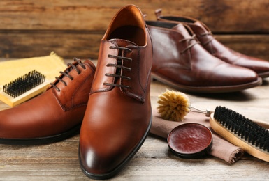 Shoe care accessories and footwear on wooden table, closeup