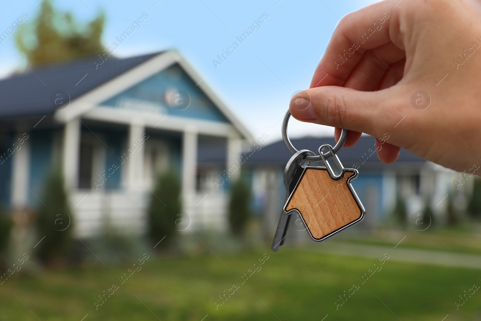 Photo of Woman holding house keys outdoors, closeup with space for text. Real estate agent