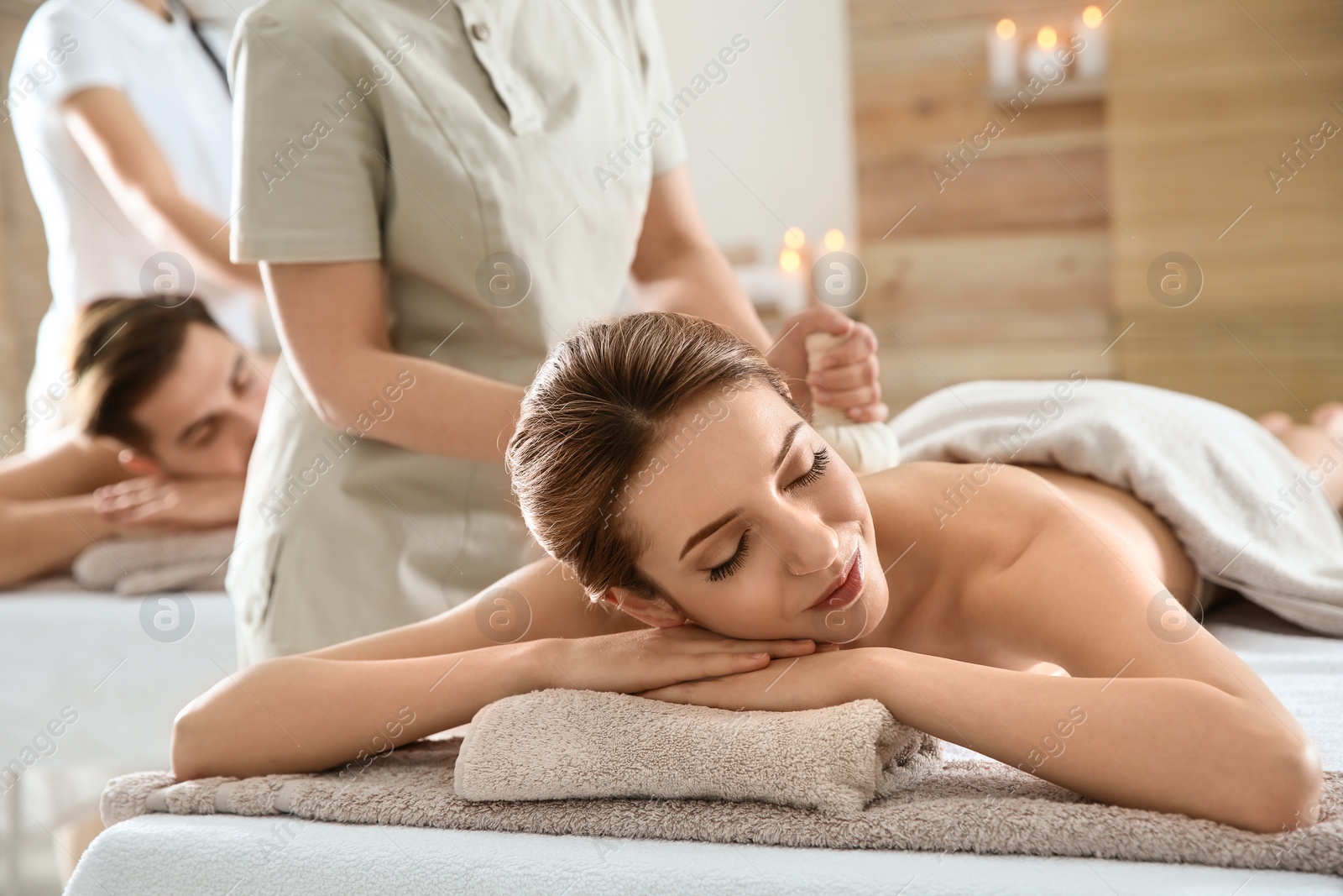 Photo of Romantic young couple enjoying herbal bag massage in spa salon