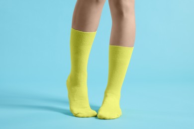 Photo of Woman in stylish yellow socks on light blue background, closeup