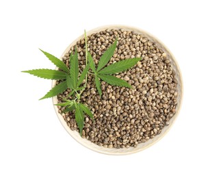 Bowl with hemp seeds and leaves on white background, top view