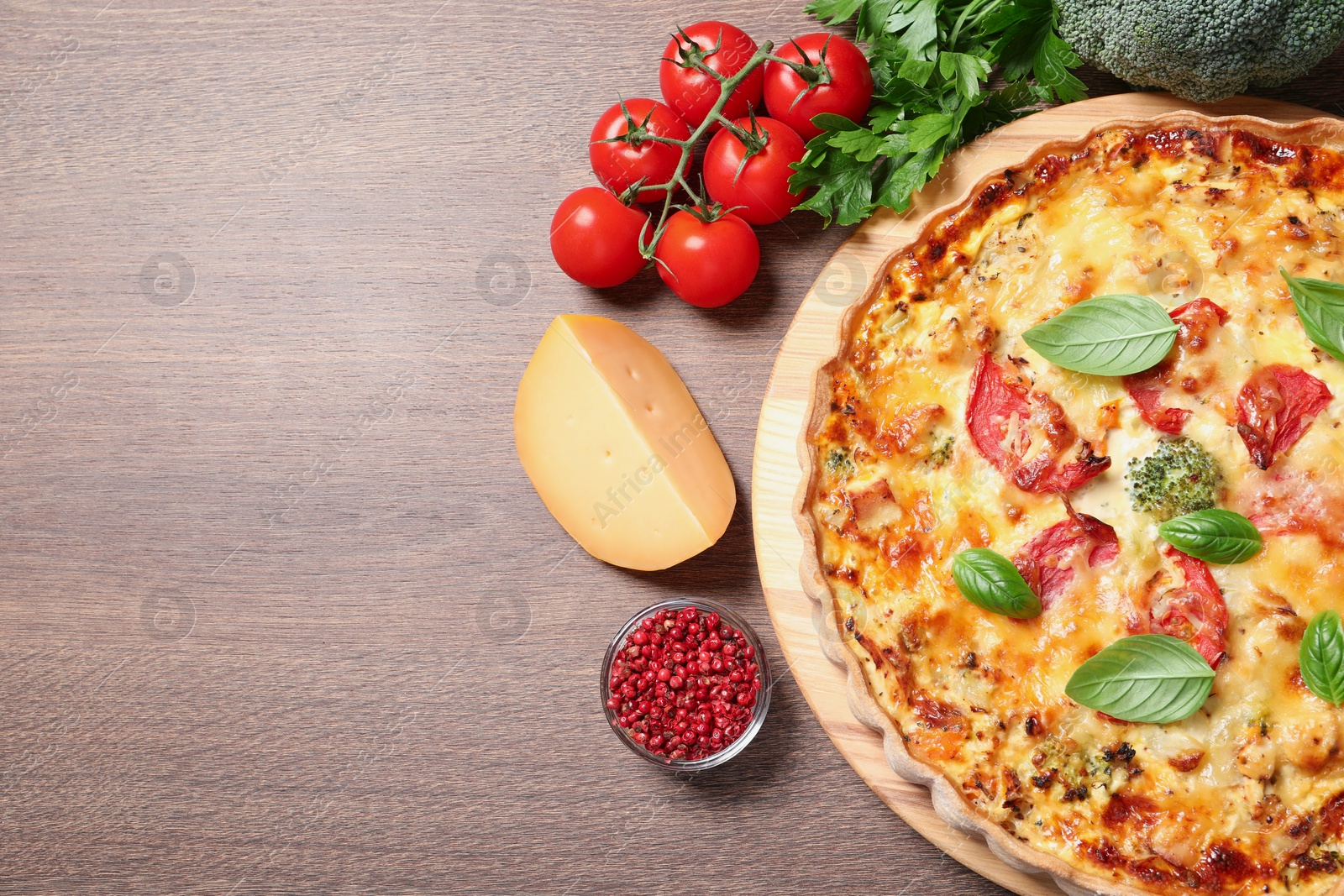 Photo of Tasty cheese quiche and ingredients on wooden table, flat lay. Space for text