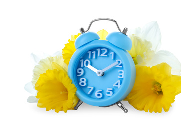 Photo of Light blue alarm clock and spring flowers on white background. Time change