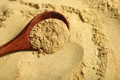 Photo of Heap of aromatic mustard powder and wooden spoon, closeup. Space for text