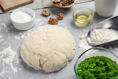 Making delicious pesto bread. Raw dough and ingredients on grey table