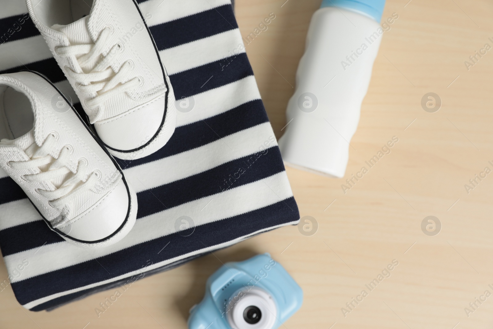 Photo of Baby clothes, shoes and accessories on wooden table, flat lay