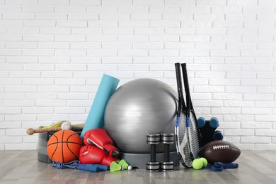 Photo of Set of different sports equipment on floor near white brick wall