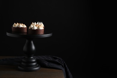 Photo of Delicious salted caramel chocolate tarts on wooden table against dark background, space for text