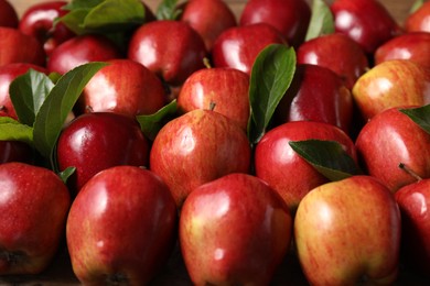 Photo of Fresh ripe red apples with leaves as background, closeup