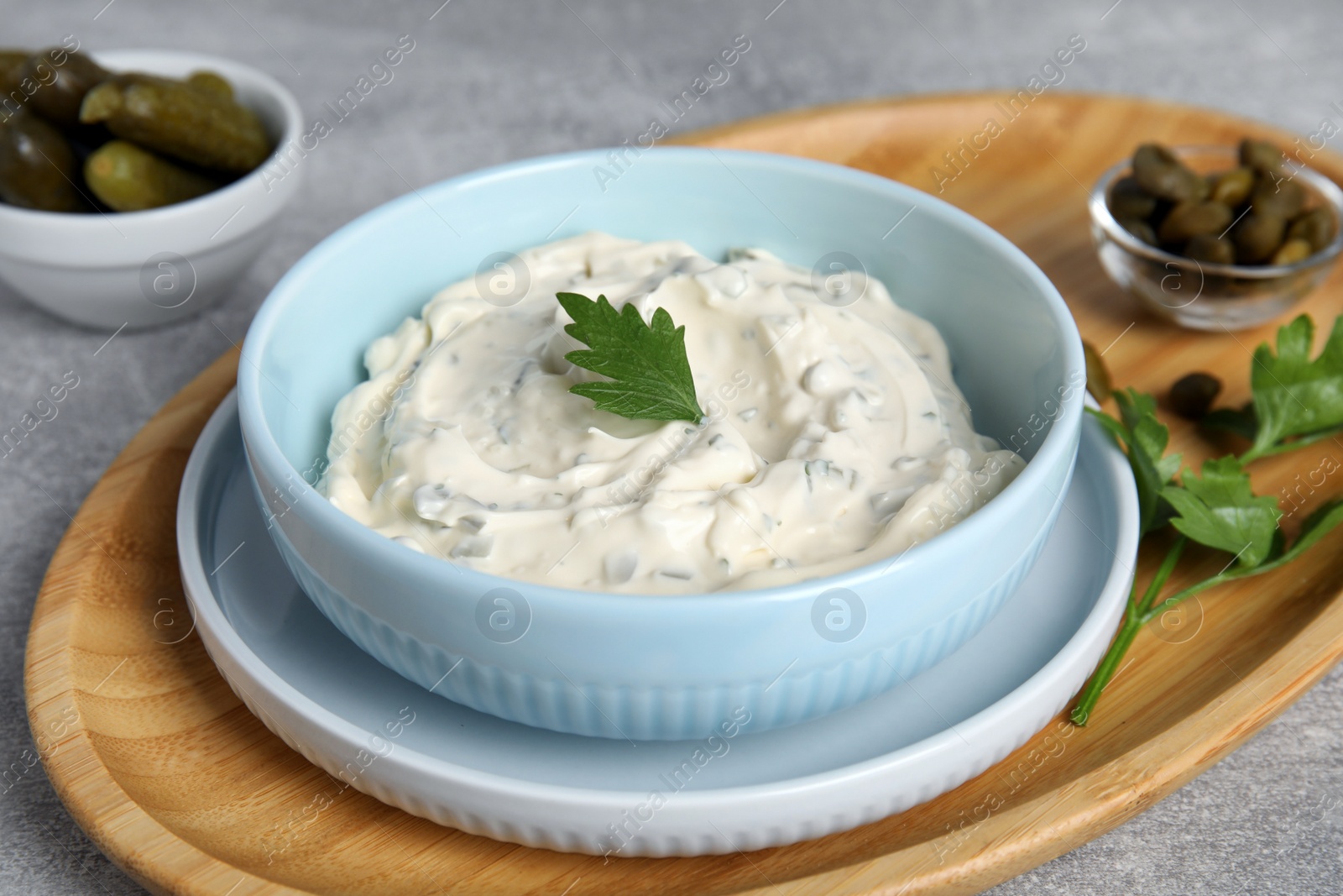 Photo of Tasty tartar sauce and ingredients on grey table, closeup