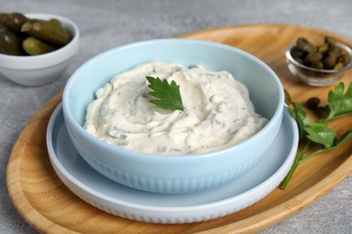 Photo of Tasty tartar sauce and ingredients on grey table, closeup