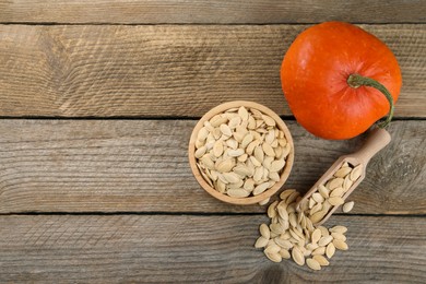 Photo of Bowl, scoop with seeds and fresh pumpkin on wooden table, flat lay. Space for text