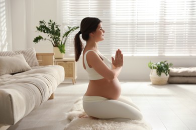 Photo of Young pregnant woman practicing yoga at home