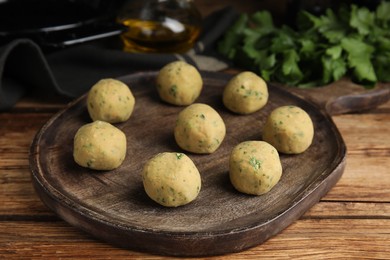 Photo of Wooden board with raw falafel balls on table