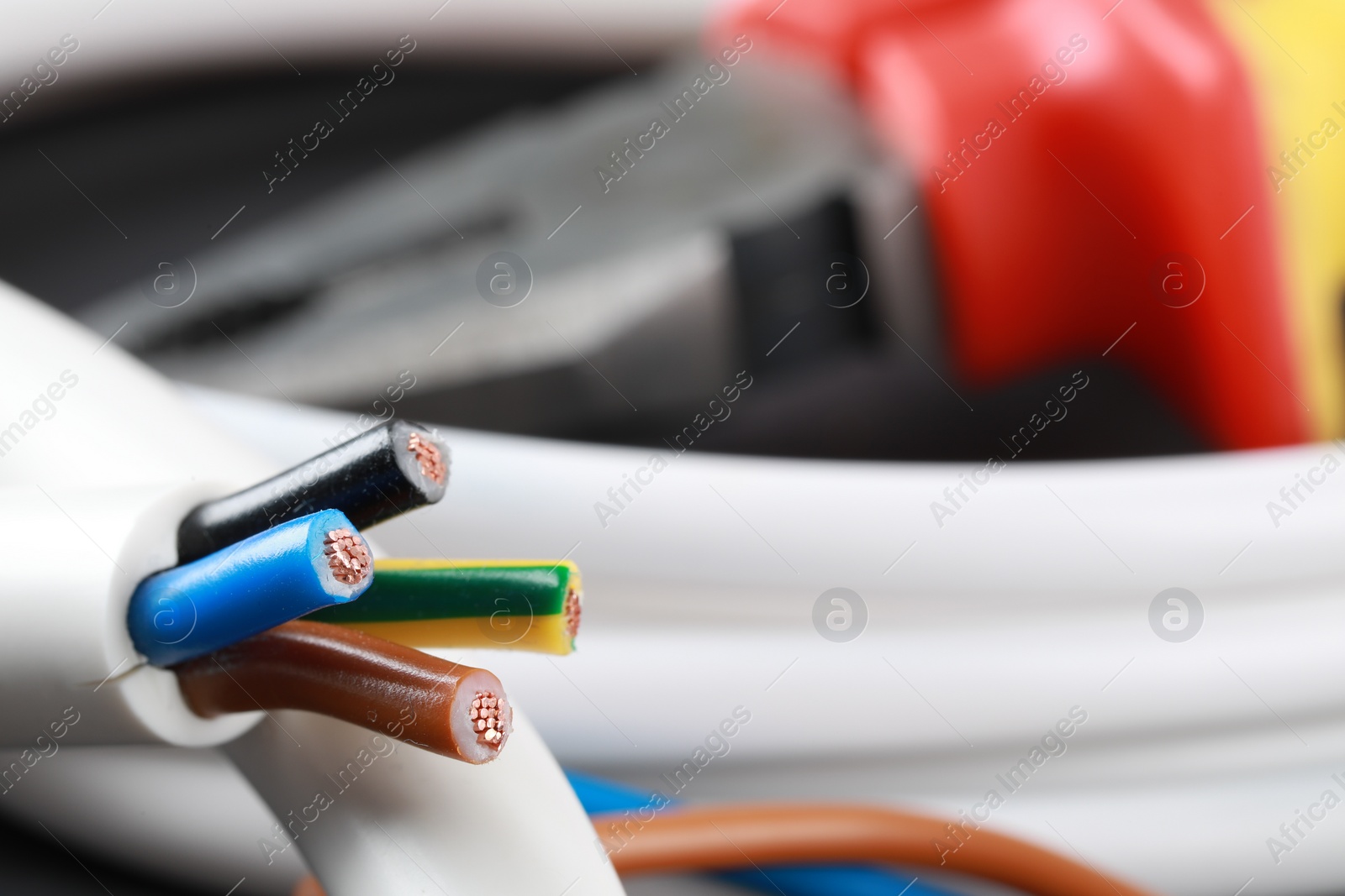 Photo of New colorful electrical wire on blurred background, closeup. Space for text