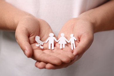 Man holding paper family figures, closeup. Insurance concept