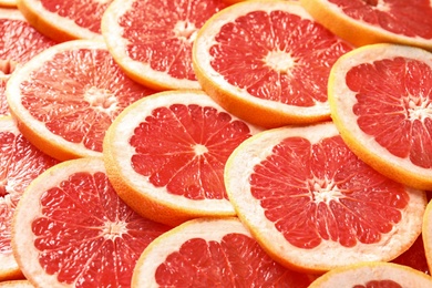 Photo of Many sliced fresh ripe grapefruits as background, closeup