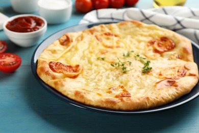 Delicious khachapuri with cheese on light blue wooden table, closeup