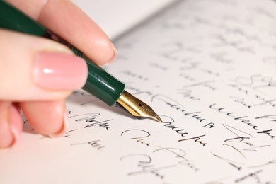 Photo of Woman writing with fountain pen in notebook, closeup