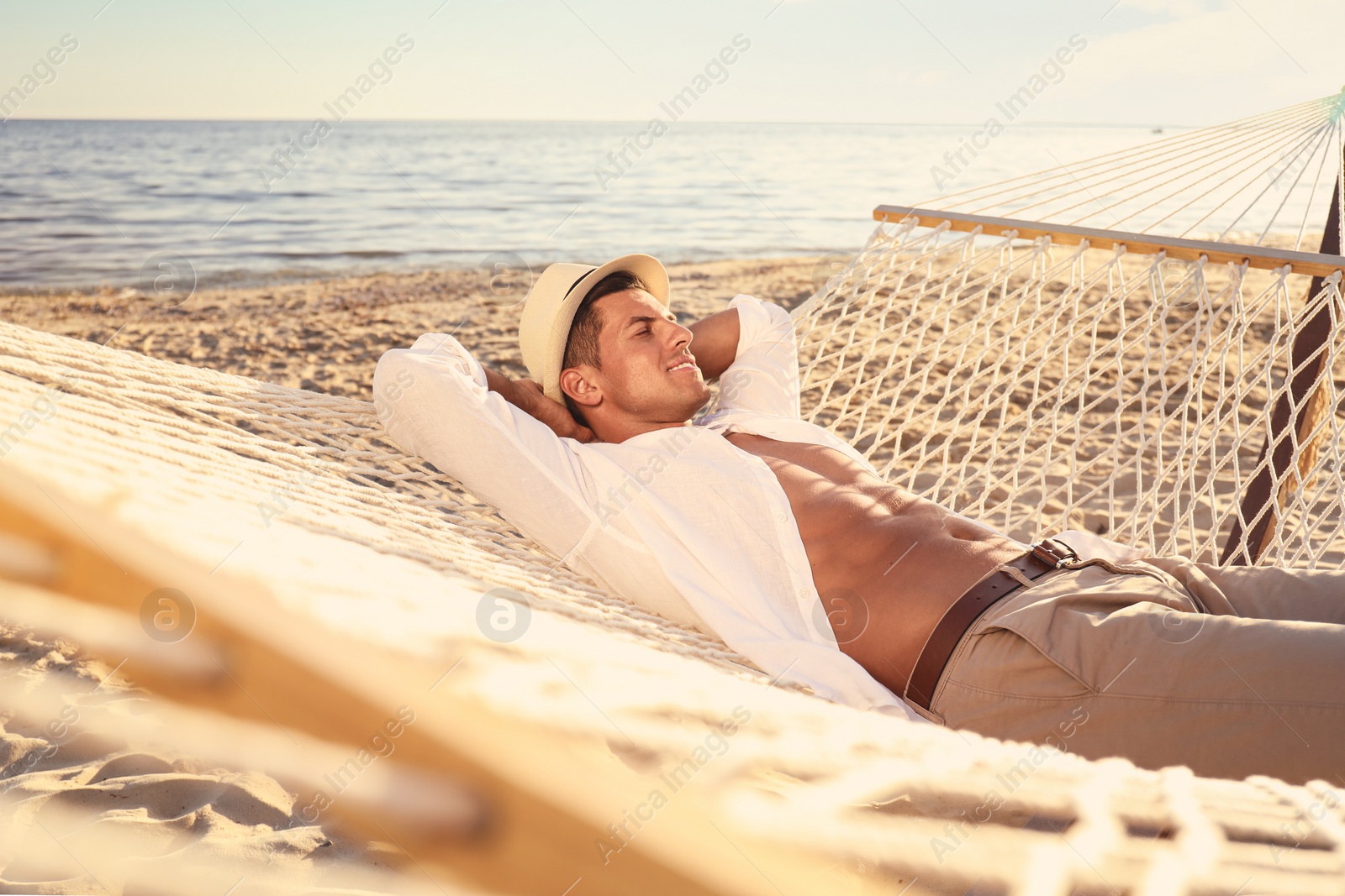 Photo of Man relaxing in hammock on beach. Summer vacation