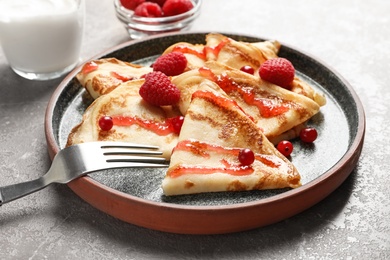 Photo of Thin pancakes served with syrup and berries on plate