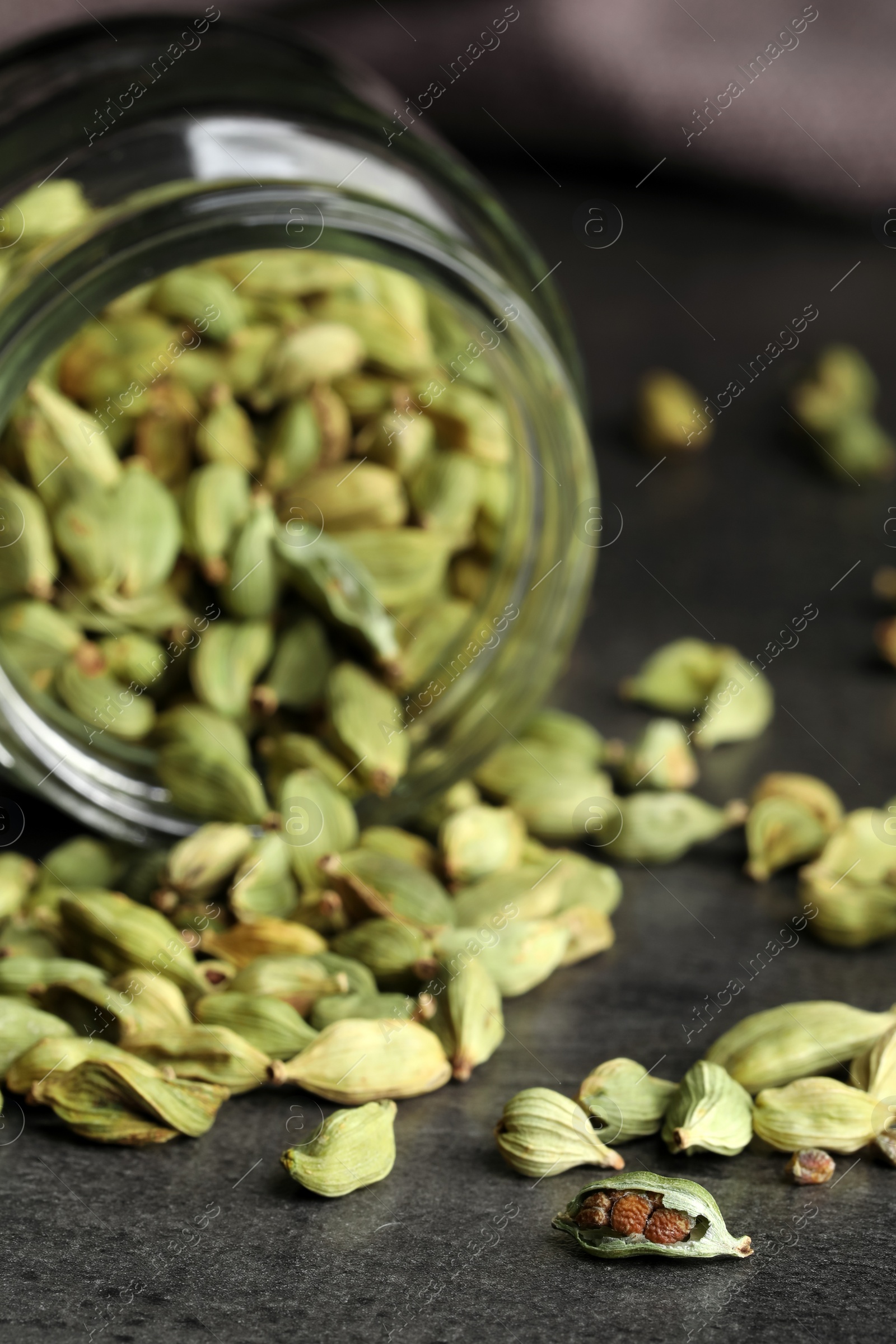 Photo of Jar with dry cardamom pods on dark grey table