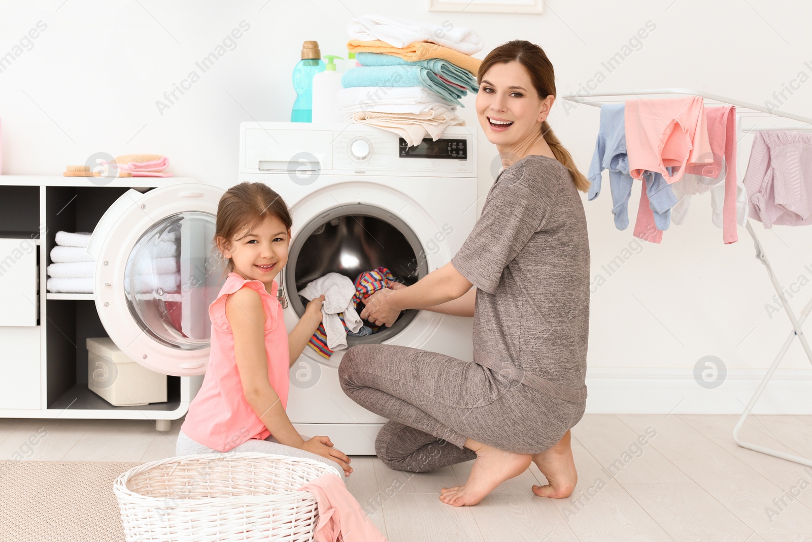 Photo of Housewife with little daughter doing laundry at home