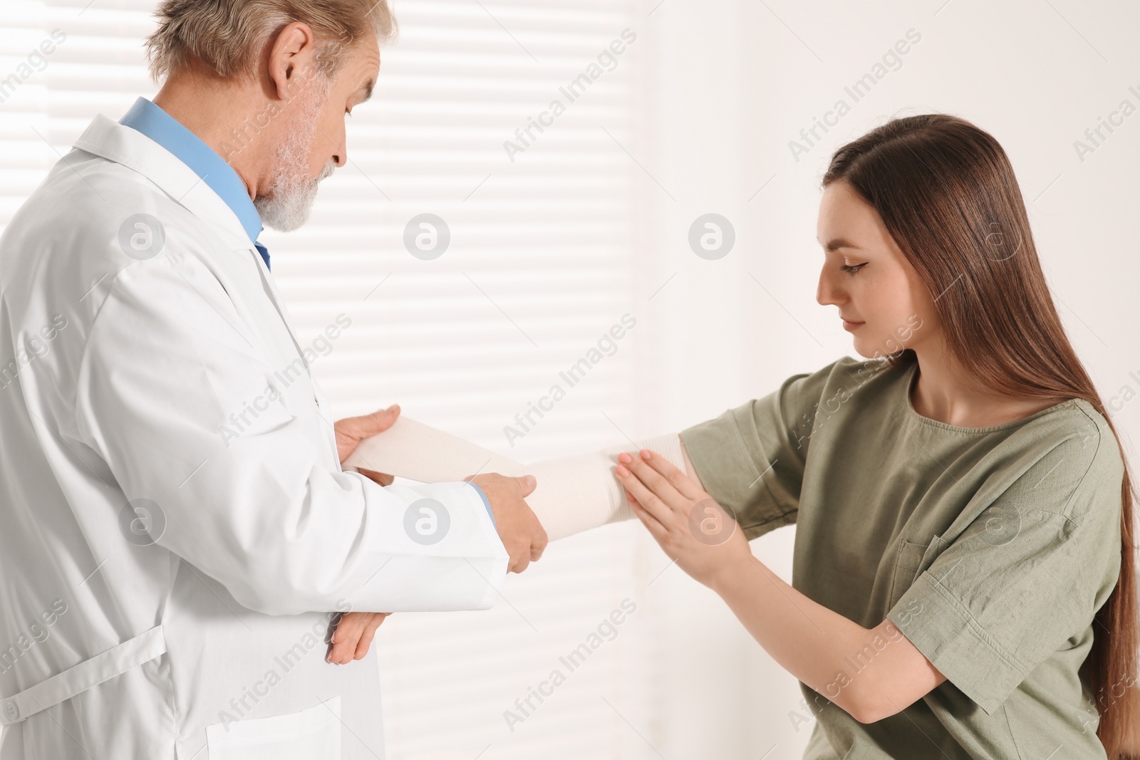 Photo of Orthopedist applying bandage onto patient's elbow in clinic