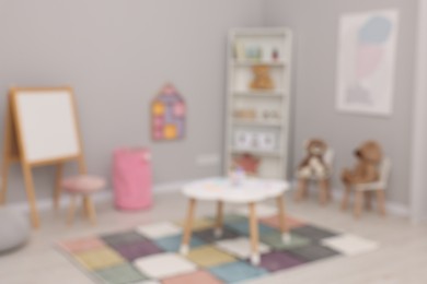 Blurred view of child`s playroom with different toys and modern furniture. Stylish kindergarten interior