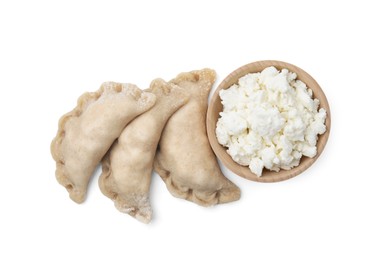 Photo of Raw dumplings (varenyky) and bowl with cottage cheese on white background, top view
