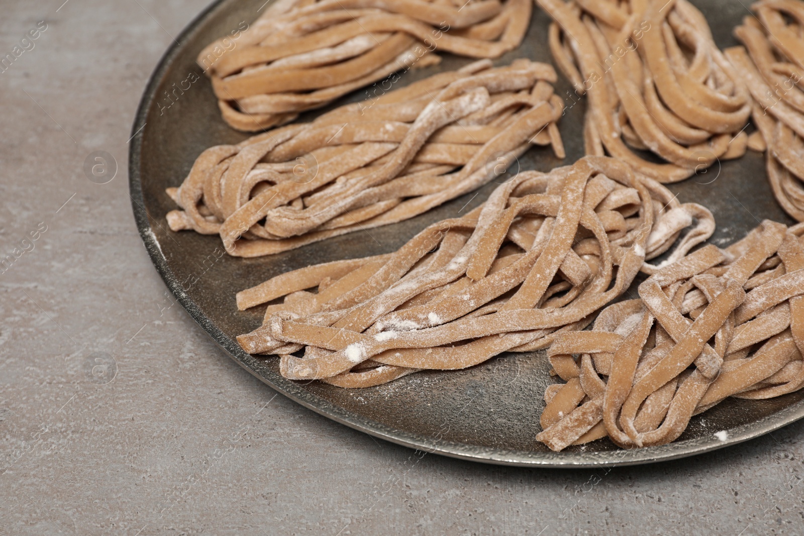 Photo of Uncooked homemade soba with tray on light table, closeup