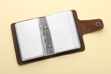Leather business card holder with blank cards on beige background, top view
