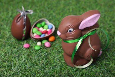 Easter celebration. Cute chocolate bunny and eggs with colorful candies on green grass