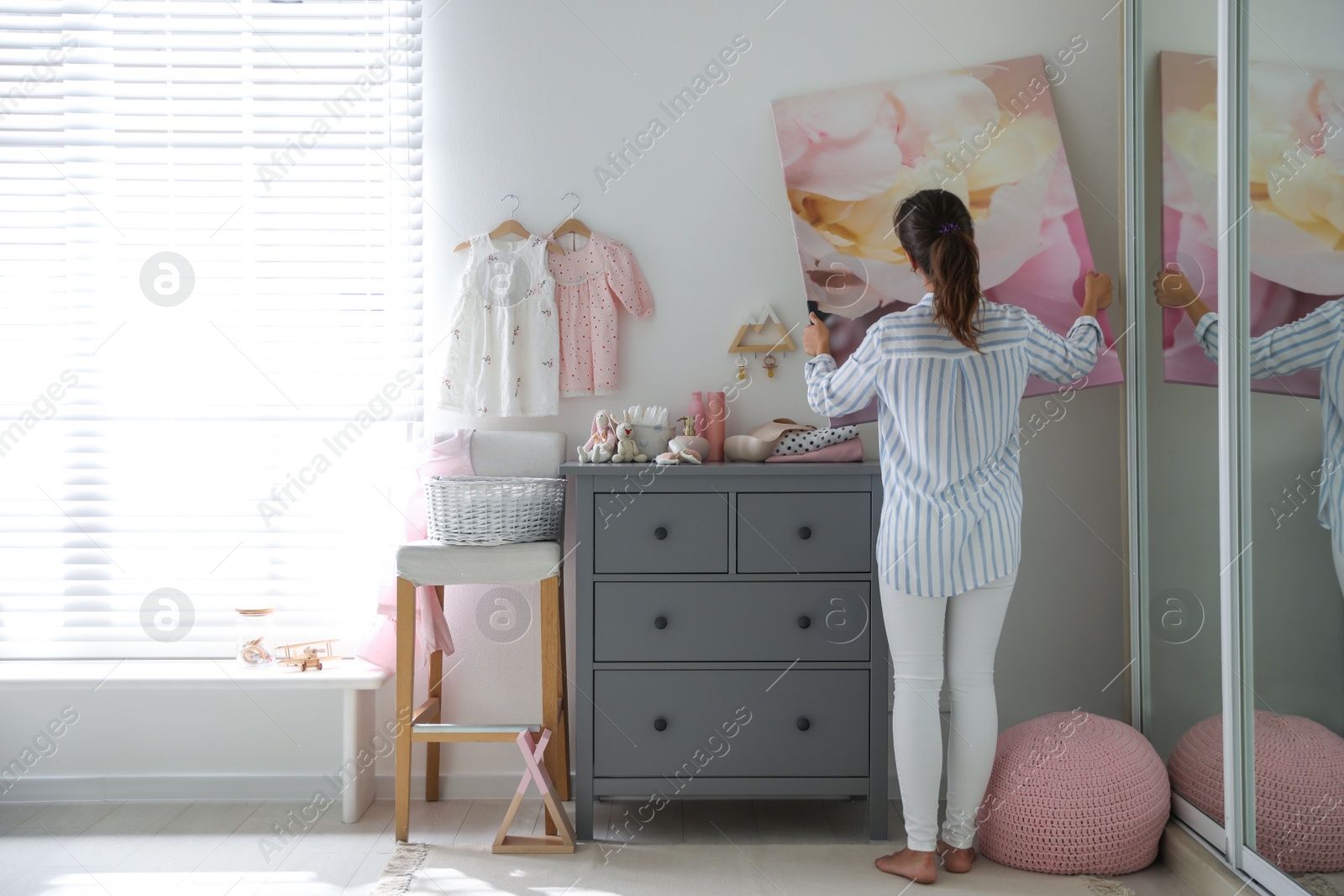 Photo of Decorator hanging picture on wall in child room. Interior design