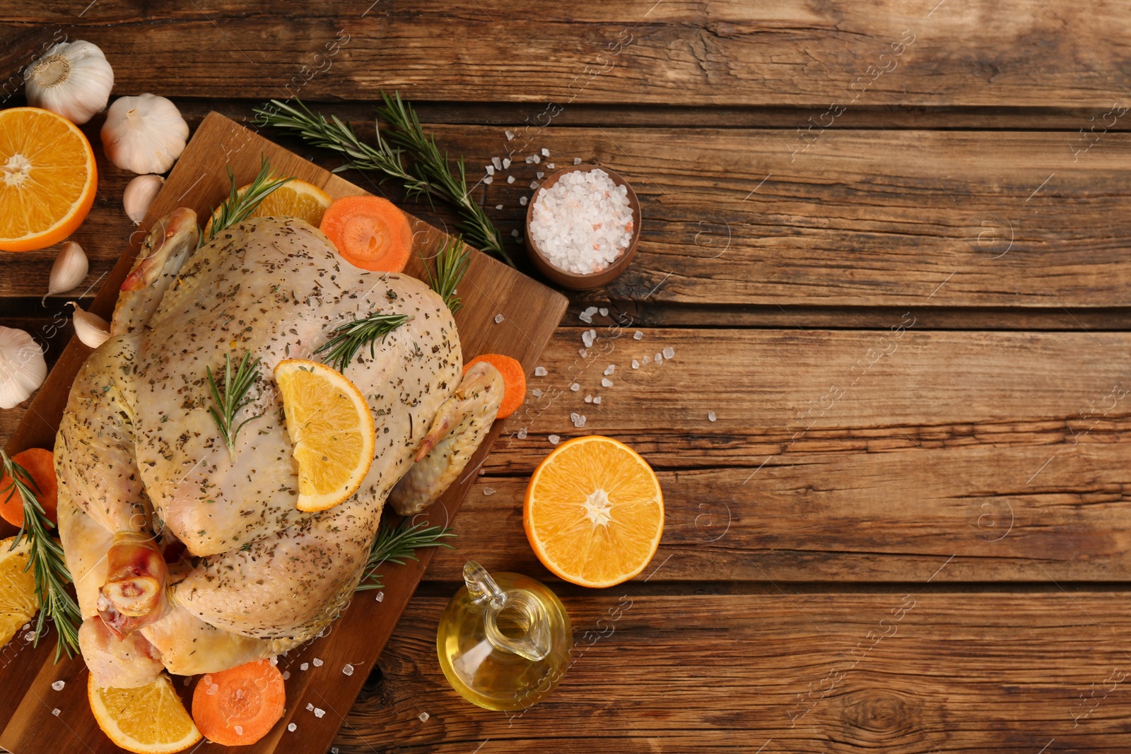 Photo of Raw chicken, orange slices and other ingredients on wooden table, flat lay. Space for text