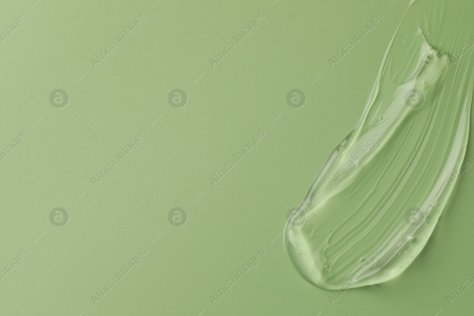 Photo of Smear of clear cosmetic gel on light green background, top view. Space for text