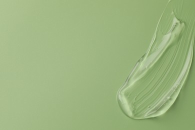 Smear of clear cosmetic gel on light green background, top view. Space for text