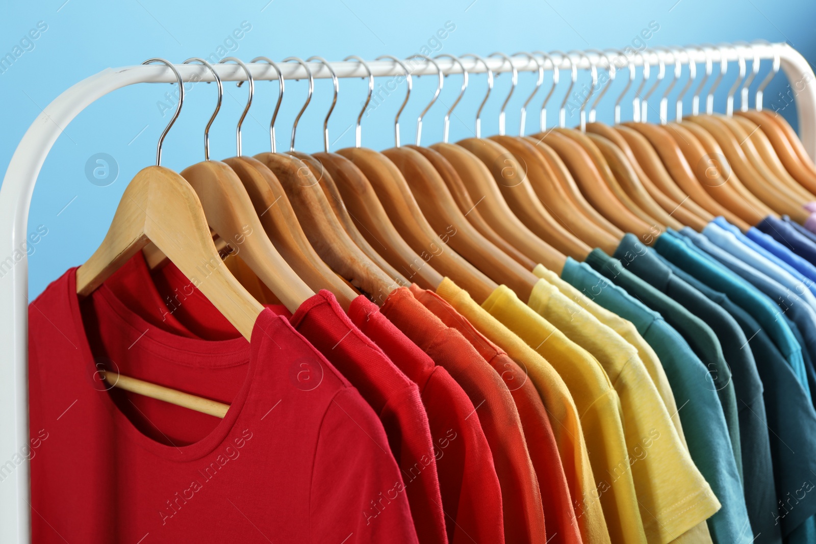 Photo of Rack with bright clothes on blue background