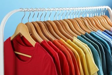 Photo of Rack with bright clothes on blue background